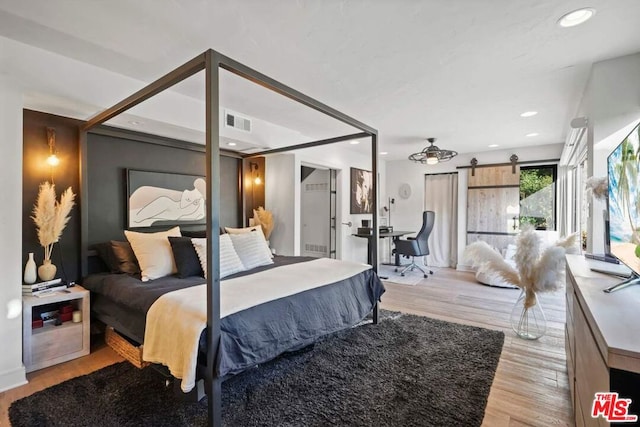 bedroom featuring a barn door and light wood-type flooring