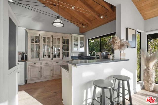 kitchen featuring wood ceiling, hanging light fixtures, a kitchen breakfast bar, light hardwood / wood-style floors, and kitchen peninsula