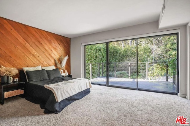 bedroom featuring carpet flooring, wooden walls, and access to exterior