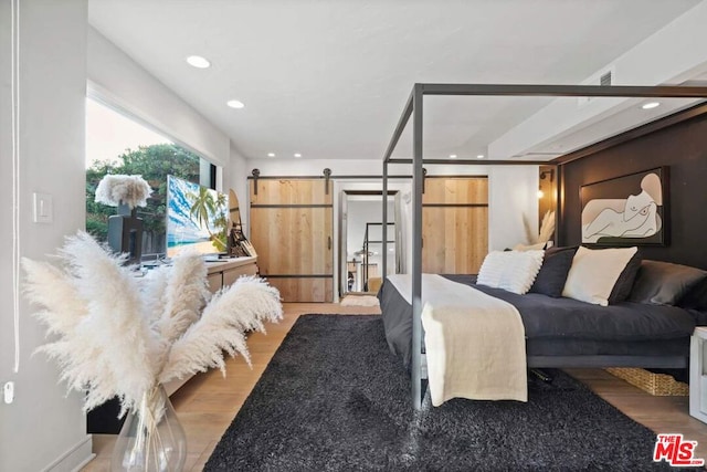 bedroom with hardwood / wood-style floors and a barn door