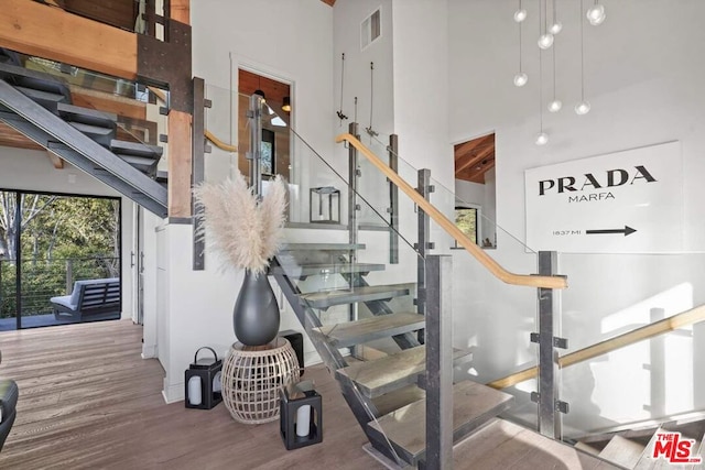 stairway featuring wood-type flooring and a high ceiling