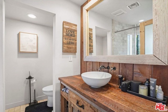 bathroom with a tile shower, vanity, and toilet