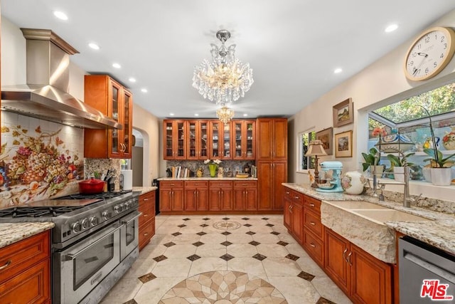 kitchen featuring light stone counters, ventilation hood, hanging light fixtures, stainless steel appliances, and backsplash