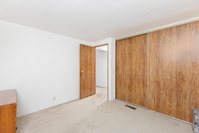 unfurnished bedroom featuring light carpet and a closet