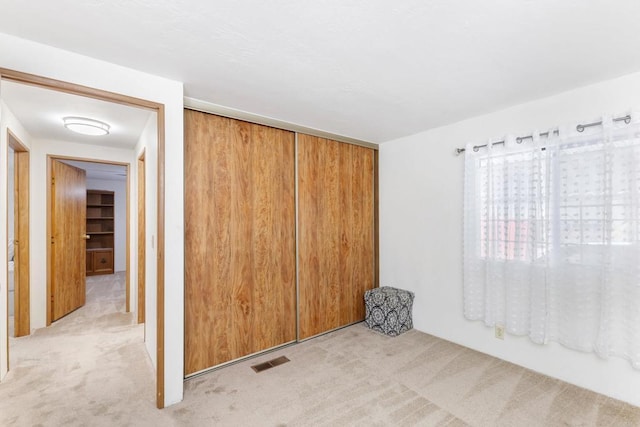 unfurnished bedroom featuring light carpet and a closet