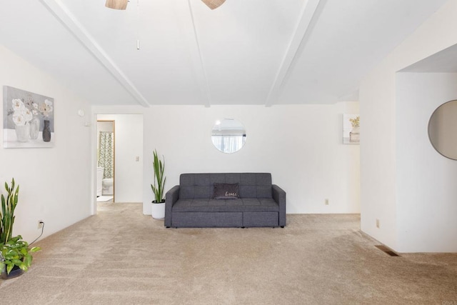 sitting room with beamed ceiling, light carpet, and ceiling fan