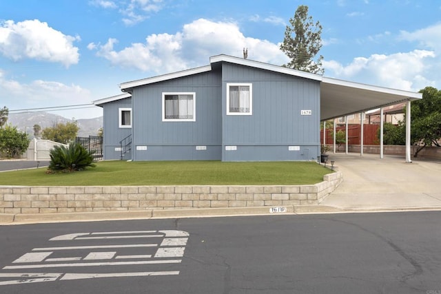 view of home's exterior featuring a carport, a mountain view, and a lawn