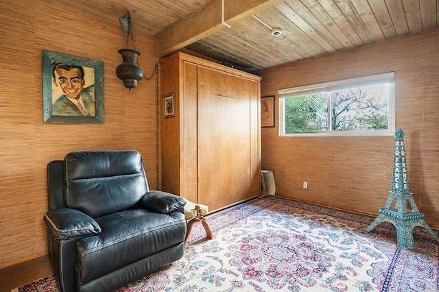 sitting room with wood ceiling, beam ceiling, and wooden walls