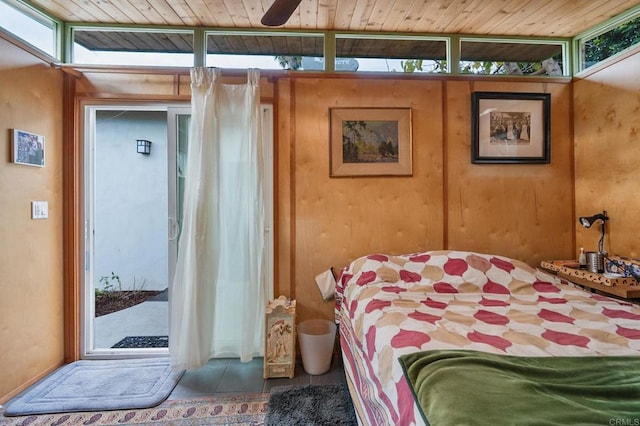 bedroom with multiple windows, ceiling fan, and wood walls