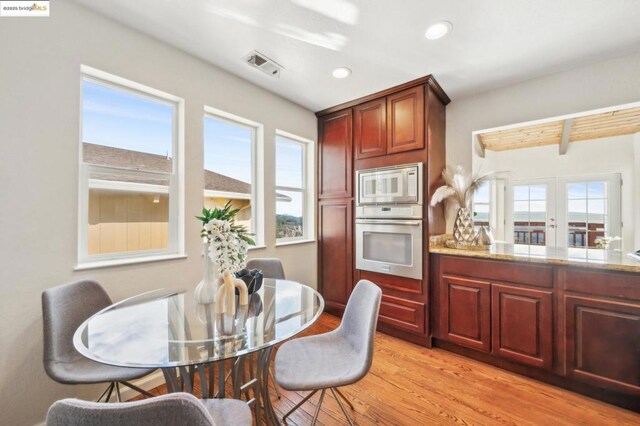 kitchen with stainless steel appliances, light stone counters, and light hardwood / wood-style floors