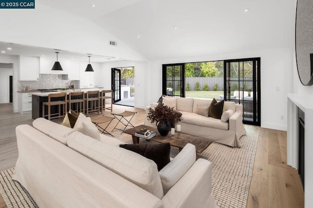 living room featuring high vaulted ceiling, light hardwood / wood-style floors, and sink