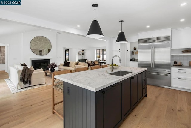 kitchen featuring pendant lighting, sink, white cabinets, and stainless steel built in fridge