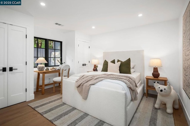 bedroom with two closets and wood-type flooring