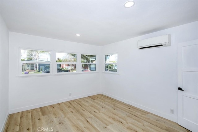 empty room featuring a wealth of natural light, light hardwood / wood-style floors, and a wall mounted AC