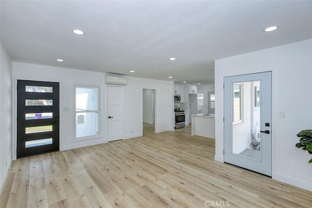 entrance foyer with a wall mounted air conditioner, plenty of natural light, and light hardwood / wood-style floors