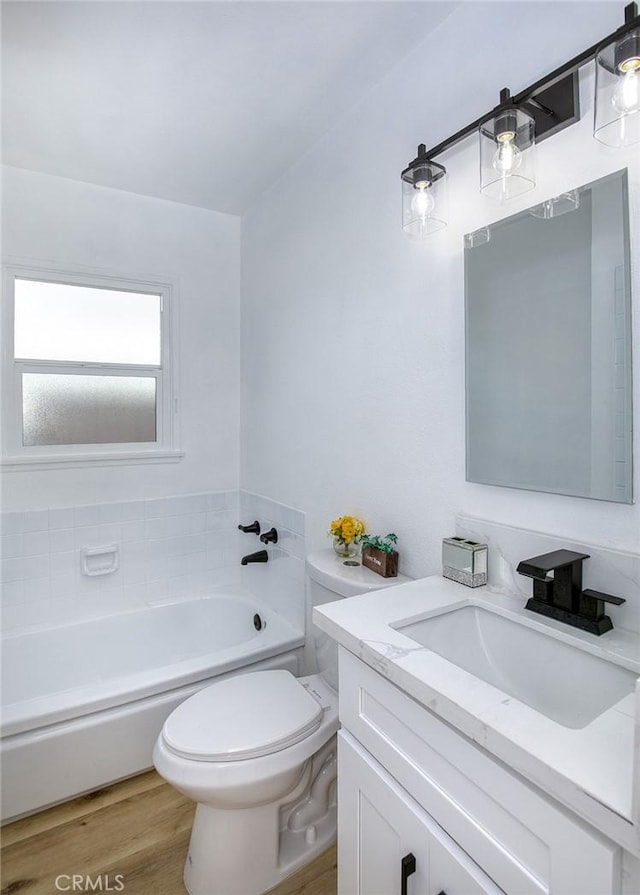 bathroom with wood-type flooring, a tub, vanity, and toilet