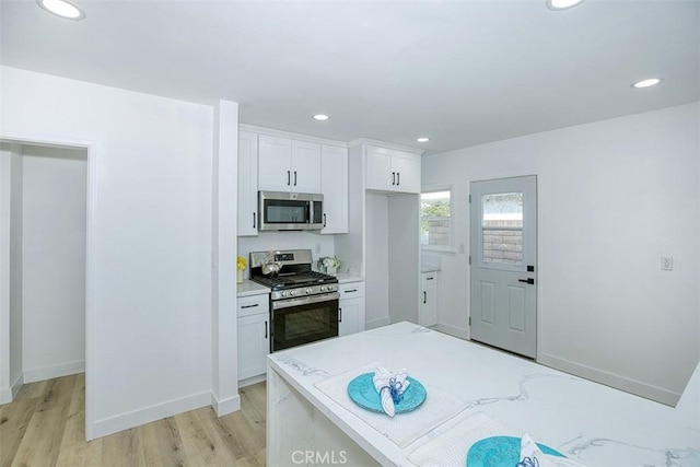 kitchen featuring white cabinetry, light stone countertops, light hardwood / wood-style flooring, and stainless steel appliances