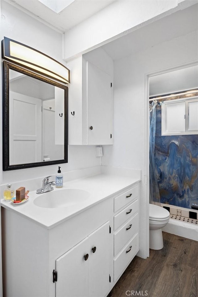 bathroom featuring hardwood / wood-style flooring, vanity, toilet, and curtained shower