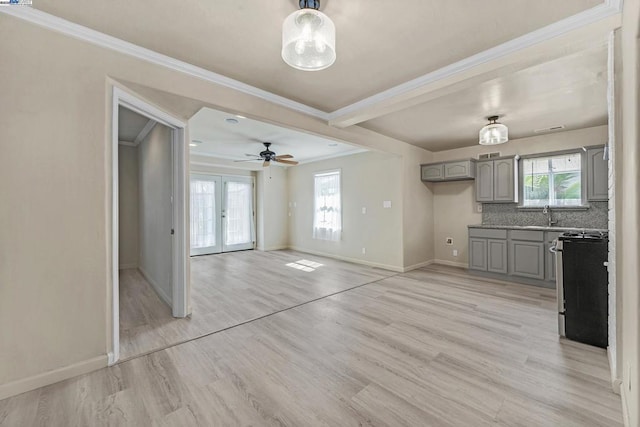 unfurnished living room featuring sink, a wealth of natural light, light hardwood / wood-style floors, and french doors