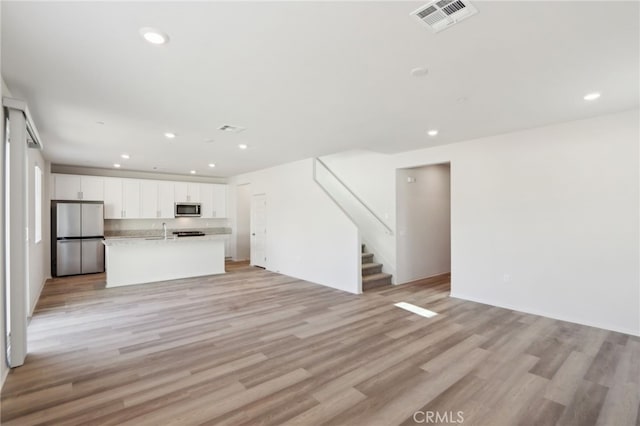 unfurnished living room with sink and light wood-type flooring