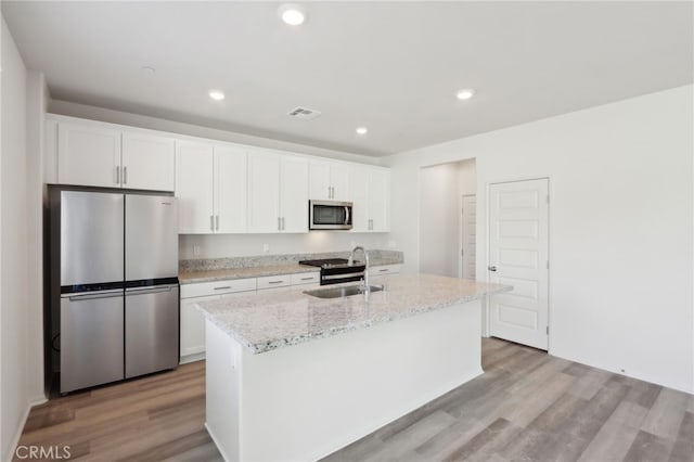 kitchen featuring stainless steel appliances, an island with sink, sink, and white cabinets