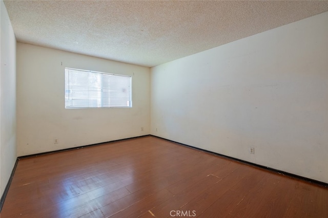 unfurnished room featuring wood-type flooring and a textured ceiling