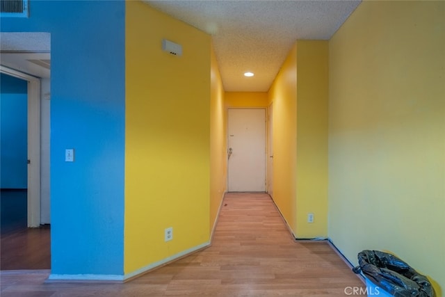 hall featuring light hardwood / wood-style floors and a textured ceiling