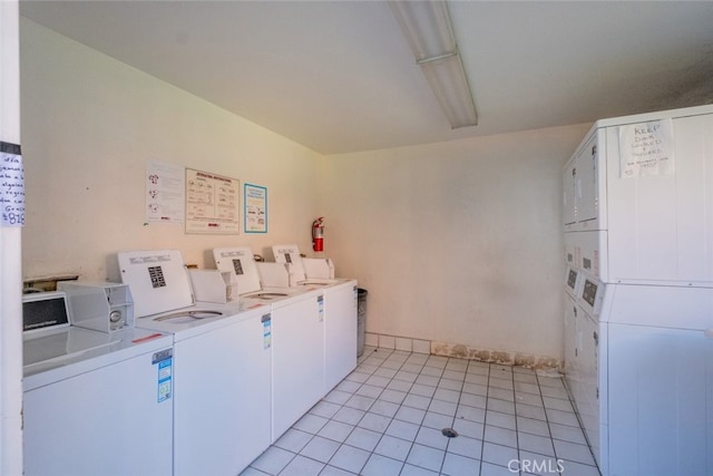 laundry room with stacked washer / dryer, light tile patterned floors, and washer and clothes dryer