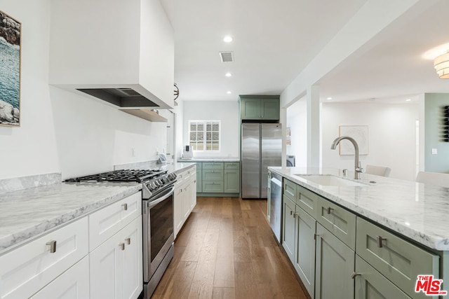 kitchen with sink, white cabinets, hardwood / wood-style flooring, stainless steel appliances, and light stone countertops