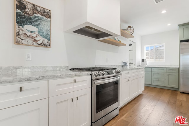 kitchen with green cabinets, white cabinetry, appliances with stainless steel finishes, custom range hood, and light wood-type flooring