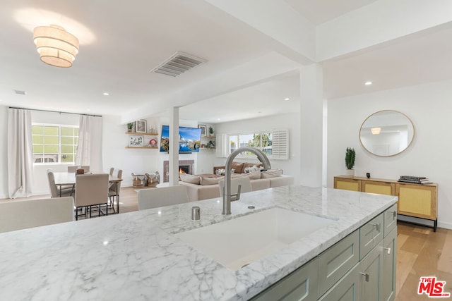 kitchen featuring sink, light stone countertops, and light wood-type flooring