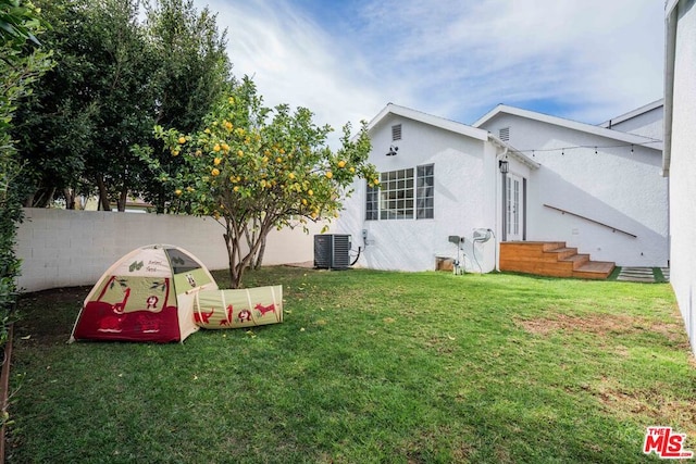 back of house featuring central AC unit and a lawn