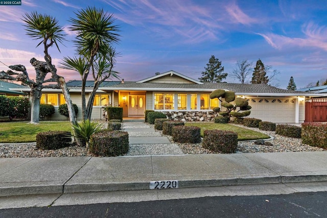 single story home with a garage and a lawn