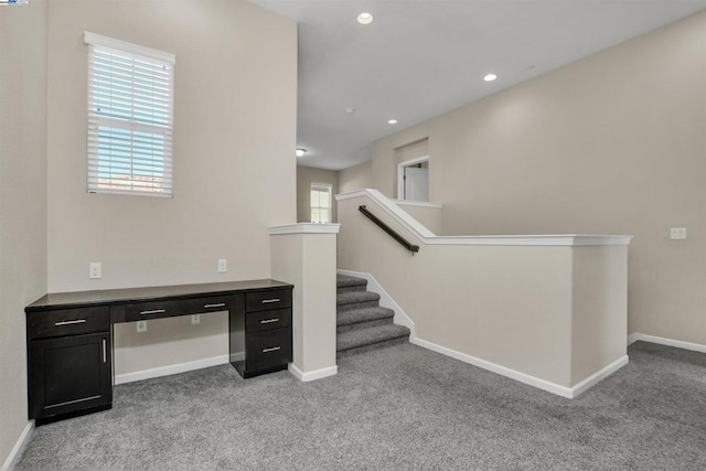 unfurnished office featuring built in desk and light carpet