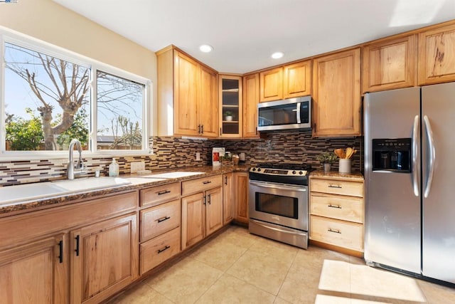 kitchen featuring sink, light tile patterned floors, appliances with stainless steel finishes, backsplash, and light stone countertops