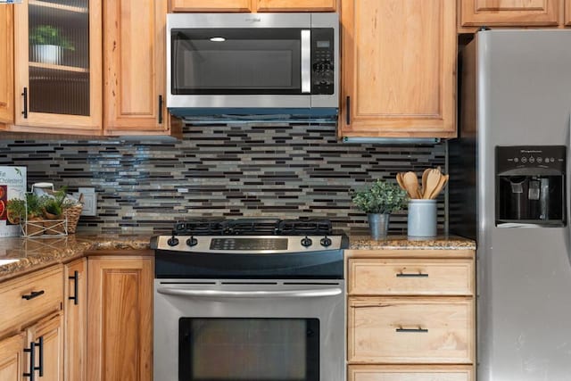 kitchen with appliances with stainless steel finishes, decorative backsplash, and dark stone counters