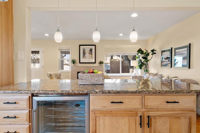 kitchen with wine cooler, pendant lighting, light stone countertops, and light brown cabinets