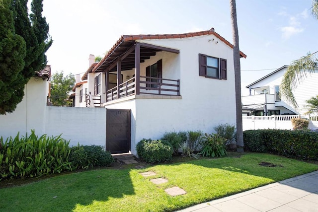 view of front of home with a balcony and a front yard