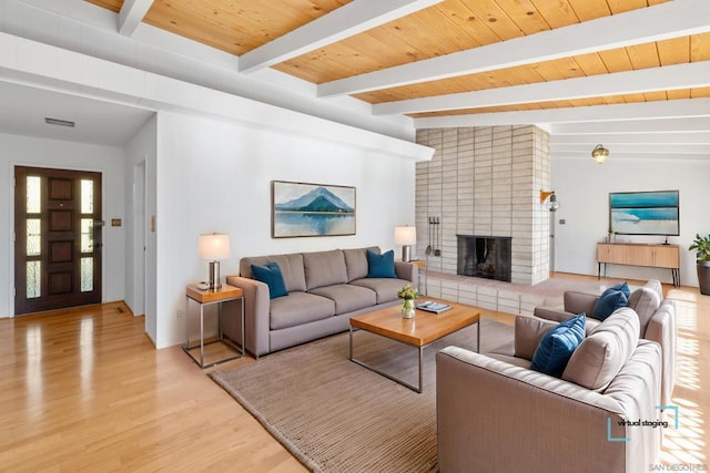 living room with beamed ceiling, wood ceiling, a fireplace, and light hardwood / wood-style flooring