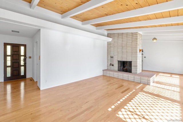 unfurnished living room featuring a fireplace, beam ceiling, light hardwood / wood-style floors, and wooden ceiling