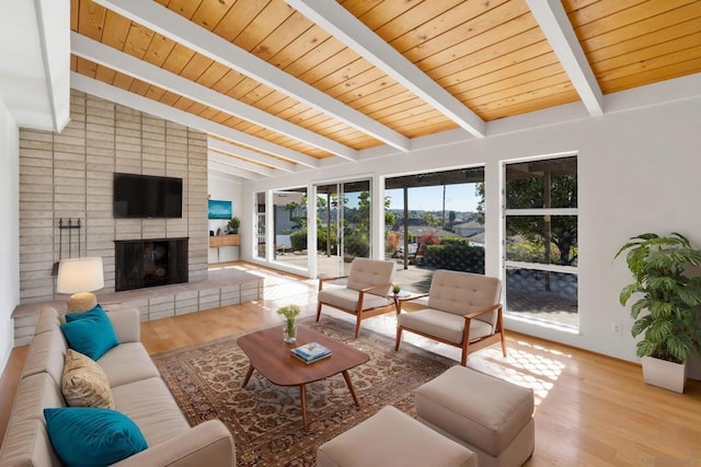 living room featuring a brick fireplace, wood ceiling, light hardwood / wood-style floors, and vaulted ceiling with beams