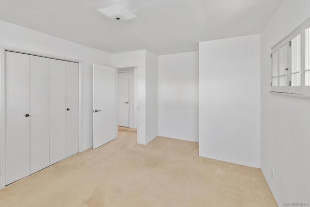 unfurnished bedroom featuring light colored carpet and a closet