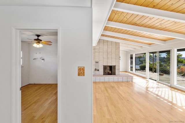 unfurnished living room featuring hardwood / wood-style flooring, ceiling fan, a fireplace, and vaulted ceiling with beams