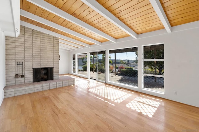 unfurnished living room featuring vaulted ceiling with beams, wood ceiling, a fireplace, and light wood-type flooring