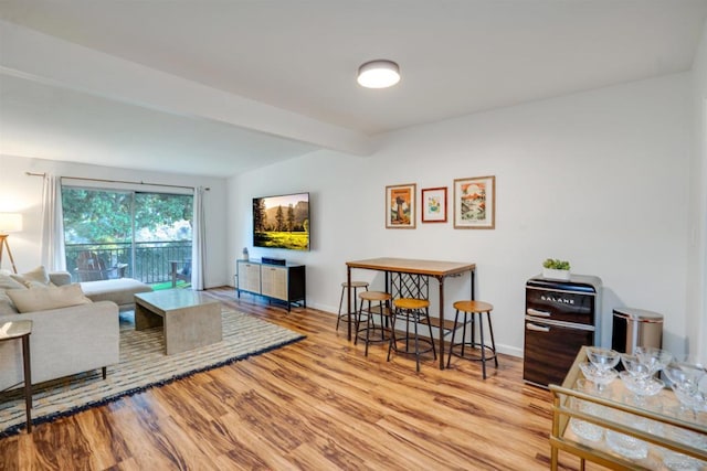 living room featuring beamed ceiling and light wood-type flooring