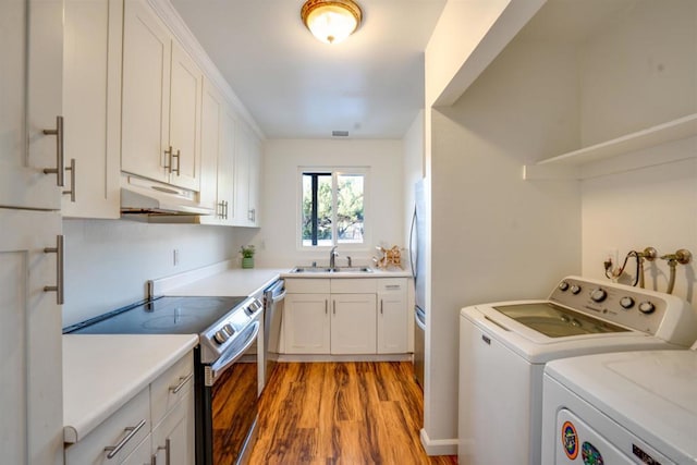 clothes washing area featuring separate washer and dryer, sink, and light wood-type flooring