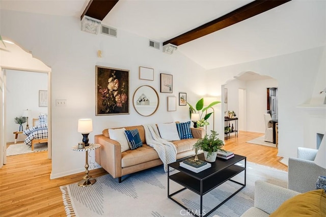 living room with vaulted ceiling with beams and light wood-type flooring