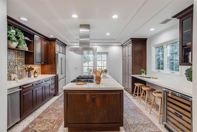 kitchen with island range hood, sink, beverage cooler, backsplash, and stainless steel appliances