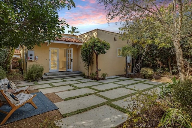 back house at dusk with a patio area and french doors