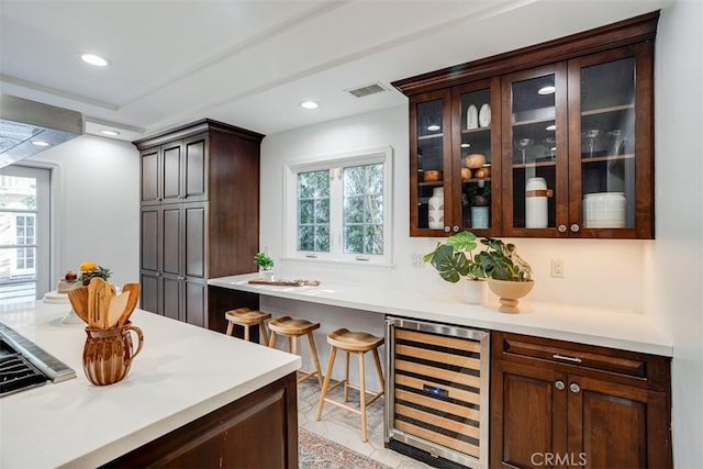 bar with beverage cooler and dark brown cabinetry